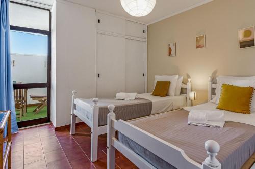 two beds in a room with a balcony at Bright 1BDR Apartment W/Balcony & Pool by LovelyStay in Silves