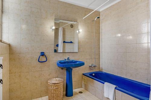 La salle de bains est pourvue d'un lavabo bleu et d'une baignoire. dans l'établissement Bright 1BDR Apartment W/Balcony & Pool by LovelyStay, à Silves