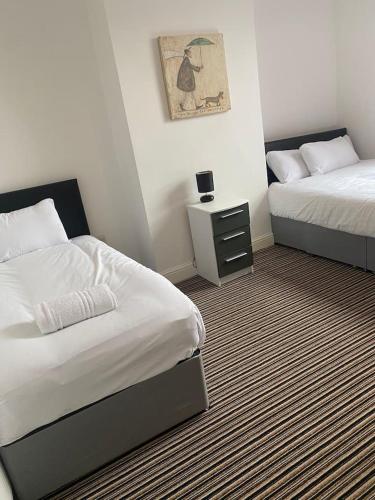 a hotel room with two beds and a night stand at Spacious house with 3 ensuite bedrooms in Leeds in Leeds