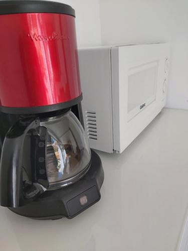 a coffee maker is sitting next to a microwave at Grand studio tout équipé in Ploërmel