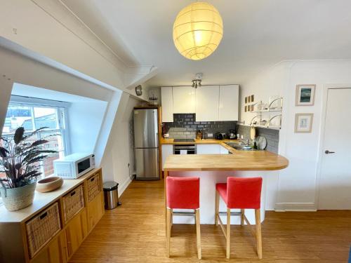 a kitchen with a wooden table and two red chairs at Bright 1 bed flat near Cabot Circus in Bristol