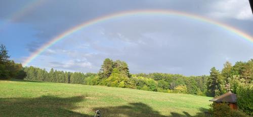 a rainbow in a field with a green field at Pension am Wald in Gößweinstein