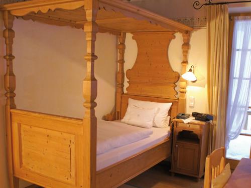 um quarto com uma cama de dossel em madeira e uma mesa de cabeceira em Landhaus Benediktenhof em Bad Tölz