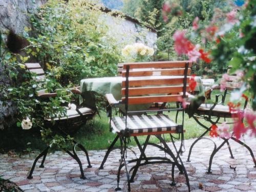 a wooden bench and a table with flowers in a garden at Landhaus Benediktenhof in Bad Tölz
