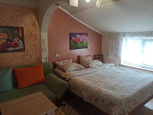 a bedroom with a bed and a couch and a window at Готель Жасмин in Ternopil