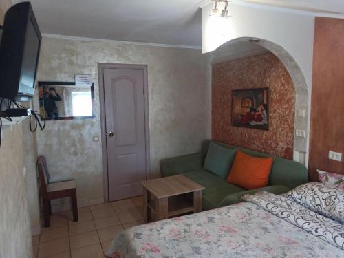 ein Schlafzimmer mit einem Bett, einem Sofa und einem Tisch in der Unterkunft Готель Жасмин in Ternopil