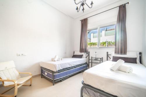 ein Schlafzimmer mit zwei Betten, einem Stuhl und einem Fenster in der Unterkunft Villa con Piscina Privada de La Torre Golf Resort Murcia - CA13LT in Torre-Pacheco