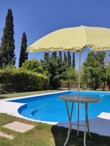 una mesa con sombrilla junto a la piscina en Cabaña sol y campo en Guaymallén