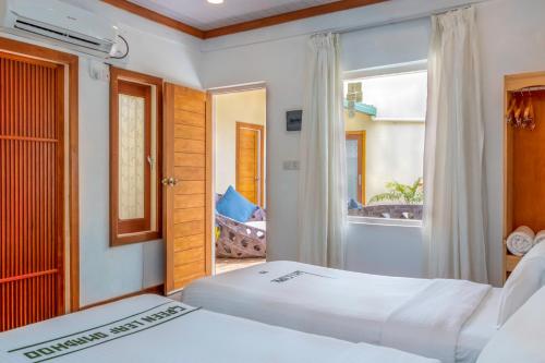 two beds in a room with a window at Green Leaf Guest House - Omadhoo in Omadhoo