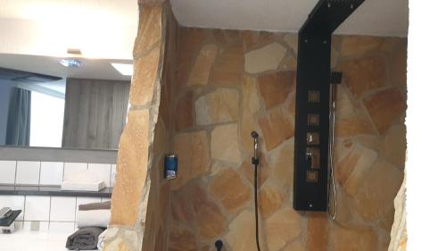 a shower in a bathroom with a stone wall at Hotel Wippertal in Bernburg