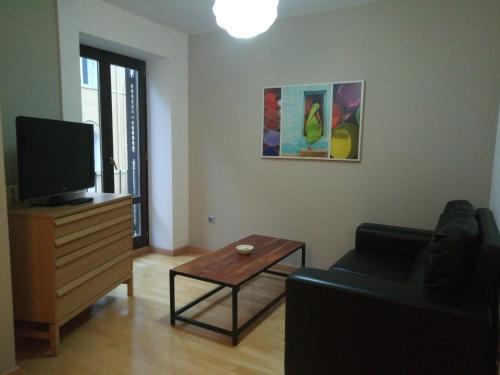 un soggiorno con TV, divano e tavolo di Apartamentos Zaragoza Coso a Saragozza