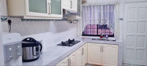 安邦的住宿－Homestay Ampang Farah，白色的厨房配有水槽和冰箱