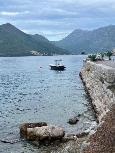 a boat in a body of water with mountains at Luxury 6 bedroom house on waterfront in Perast