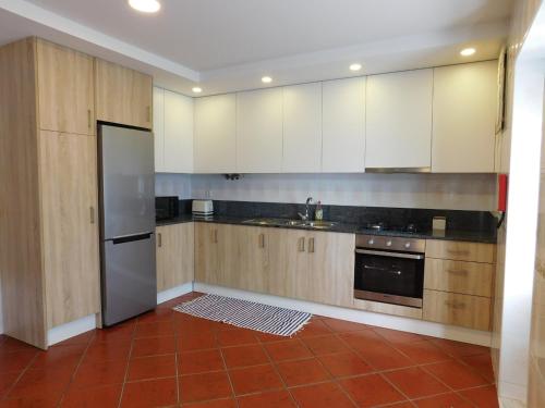 a kitchen with wooden cabinets and a stainless steel refrigerator at Casa da Veiga in Lago