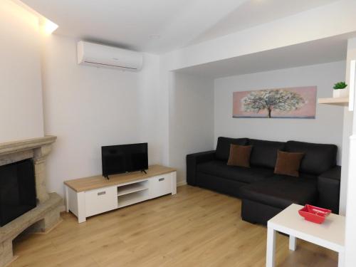 a living room with a black couch and a tv at Casa da Veiga in Lago