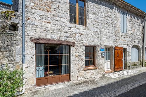 a stone building with brown doors on a street at Bastide de Tournon d'Agenais in Tournon-dʼAgenais