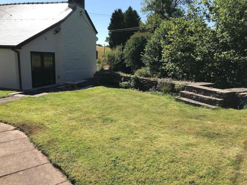 uma pequena casa branca com um jardim de relva em Cobblers Cottage in Brecon Beacons em Brecon