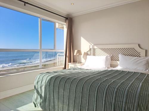 a bedroom with a bed with a view of the ocean at 3 Bedroom Sea Facing Family Apartment Cape Town Moullie Point in Cape Town