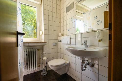 La salle de bains est pourvue d'un lavabo, de toilettes et d'une fenêtre. dans l'établissement Otto's Parkhotel Saarlouis, à Sarrelouis