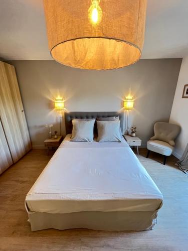 Un dormitorio con una gran cama blanca y una lámpara de araña. en Le Mas Justin, en Gordes