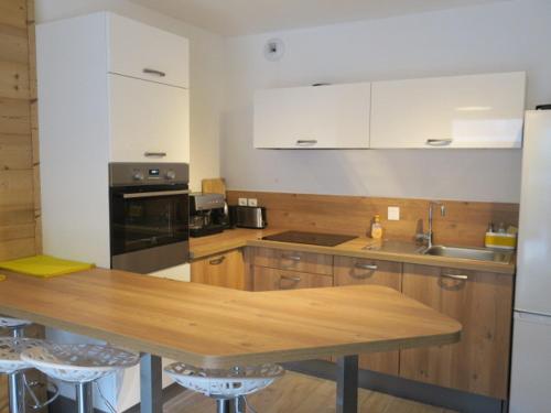 une cuisine avec des armoires en bois et une table en bois dans l'établissement Chaleureux appartement 6 personnes avec balcon et parking - Châtel - FR-1-198-147, à Châtel