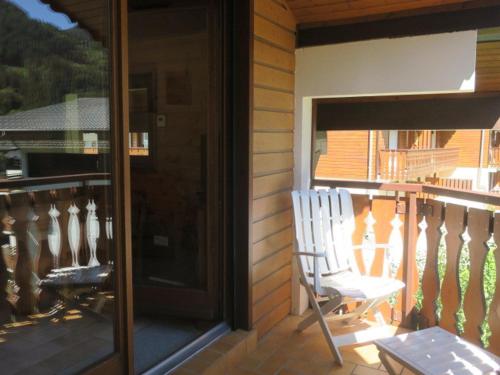 a porch with a white rocking chair on a balcony at Charmant appartement avec balcon exposé sud à Châtel - 6 personnes - FR-1-198-189 in Châtel