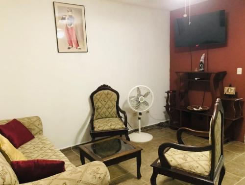 a living room with a couch and chairs and a fan at Apartamentos ipap luperon in Puerto de Luperon