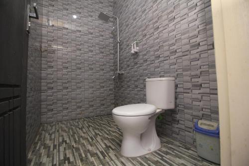a bathroom with a toilet and a brick wall at Tangkoko Lodge in Bitung