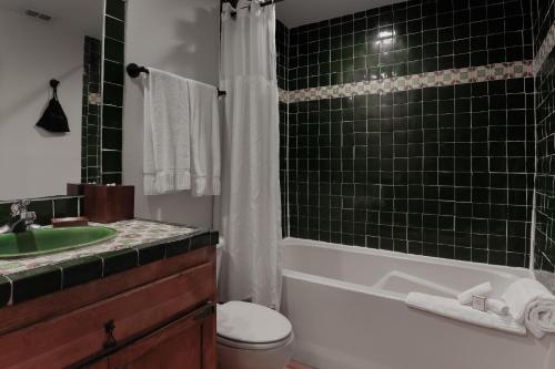 a bathroom with a green tiled shower and a toilet at The Bungalows on Shary in McAllen