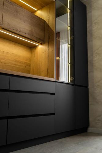 a kitchen with black cabinets and a mirror at RentWill apartments Gold in Chişinău