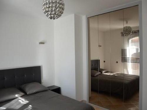- une chambre avec un lit et une porte en verre avec un miroir dans l'établissement Le petit cassis vue mer appartement 70m2 piscine, à Cassis