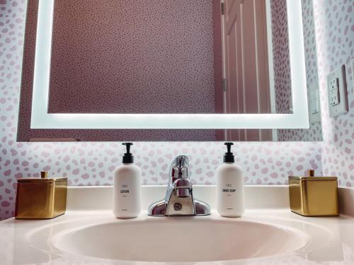 a bathroom sink with two bottles of soap and a mirror at Dolly's Delight - Boutique Bliss Mins From Broadway in Nashville
