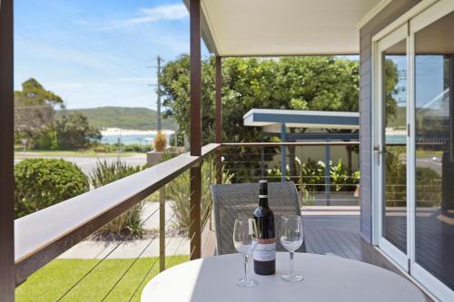 a bottle of wine sitting on a table on a balcony at Fingal Bay Beach House - Water Views and Seconds From the Beach in Fingal Bay