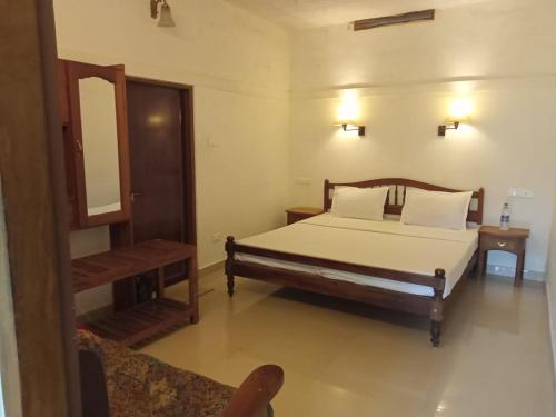 1 dormitorio con cama y espejo en Green Court Cottages, en Thekkady