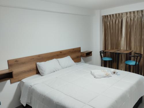 a bedroom with a large white bed with a wooden headboard at EGIPTO HOTEL BOUTIQUE in Arequipa