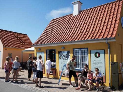a group of people standing outside of a yellow building at Holiday home Karrebæksminde LIII in Karrebæksminde