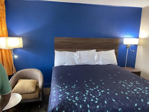 a blue bedroom with a bed and a chair at Scottish Inns - Commerce in Commerce