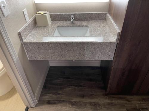 a bathroom sink with a granite counter top at Scottish Inns - Commerce in Commerce