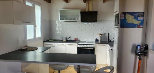 une cuisine avec des placards blancs et un comptoir noir dans l'établissement Maison entre Terre et Mer avec Jacuzzi, à Sauzon