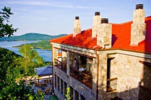 a building with a red roof with a view of the water at Χρυσοπελεια - Chrisopeleia Lake View in Neochori