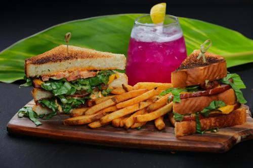 a sandwich and french fries on a wooden plate with a drink at The Bungalows on Shary in McAllen