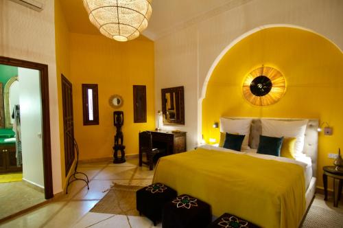 a bedroom with a bed with a yellow wall at La Claire Fontaine in Marrakech