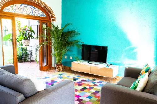 sala de estar con TV y pared azul en Colibrí Turquesa, en Tepoztlán