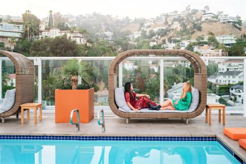 two women sitting on wicker chairs next to a swimming pool at Andaz West Hollywood-a concept by Hyatt in Los Angeles