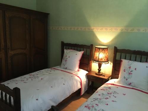 a bedroom with two beds and a lamp on a table at Les Hibiscus in Andolsheim