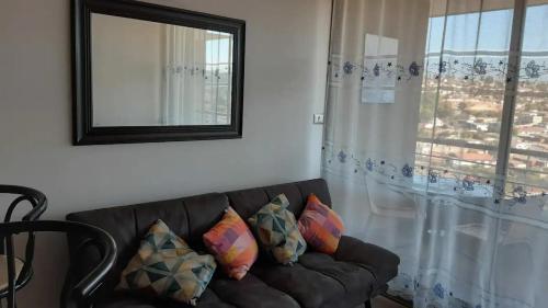 un sofá con almohadas en la sala de estar con ventana en CONDOMINIO TERRASOL 1, en Quilpué