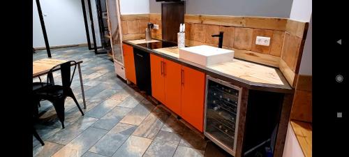 a kitchen with orange cabinets and a sink and a table at Maison chaleureuse entre Terre et Mer. in Agde