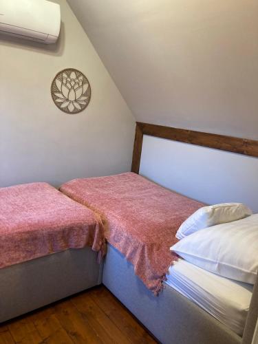a bedroom with two beds with pink sheets at Zsóka Fogadója in Szentantalfa