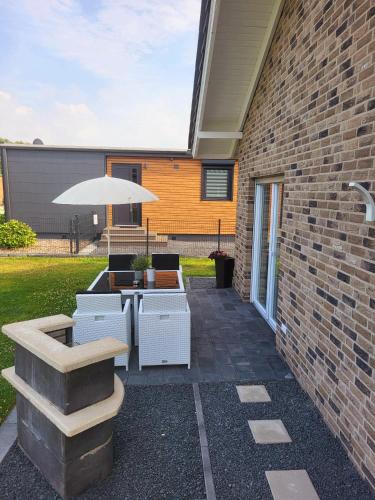 a patio with a table and an umbrella at Ferienhaus am See Goch Kessel in Goch