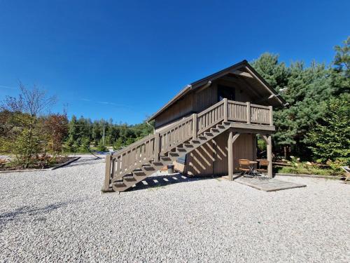 a wooden cabin with a staircase on a pile of gravel at Oberża pod Złotym Prosiakiem in Nieborów